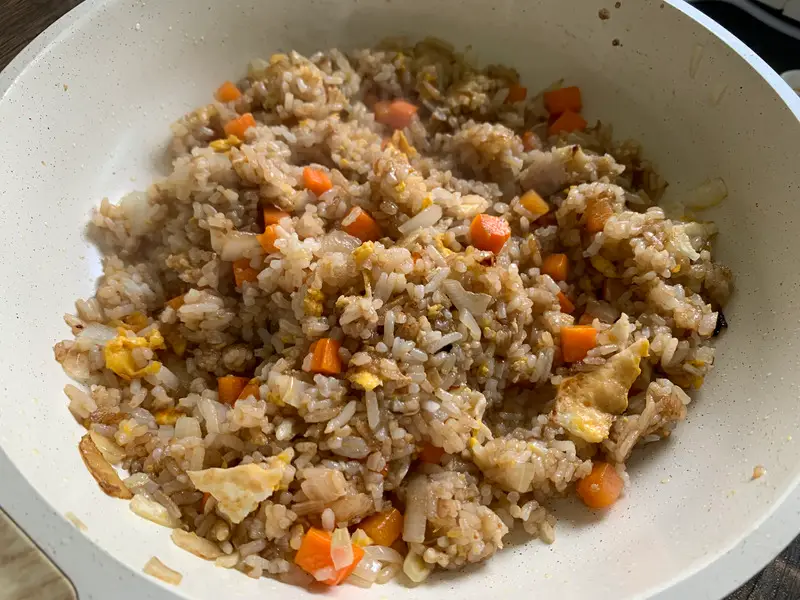Fried rice after adding sauces, starting to look golden brown.