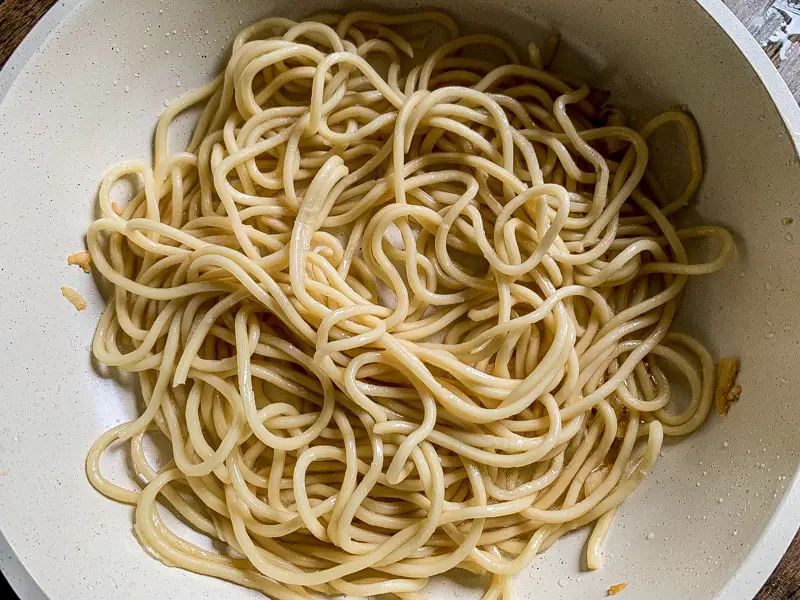 Yakisoba noodles warming in a hot pan before adding sauce and vegetables.